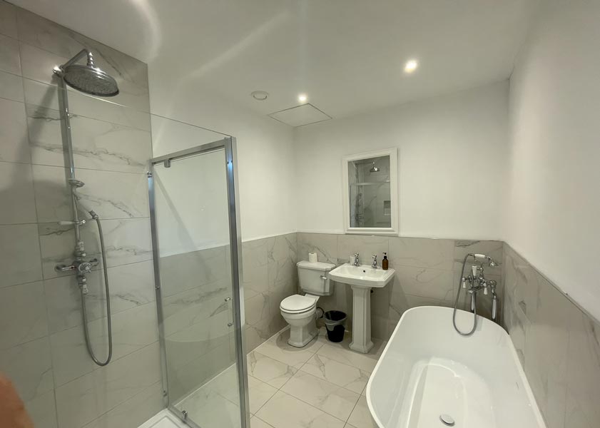 Bathroom with a freestanding bath, walk-in shower and marble-effect tiles